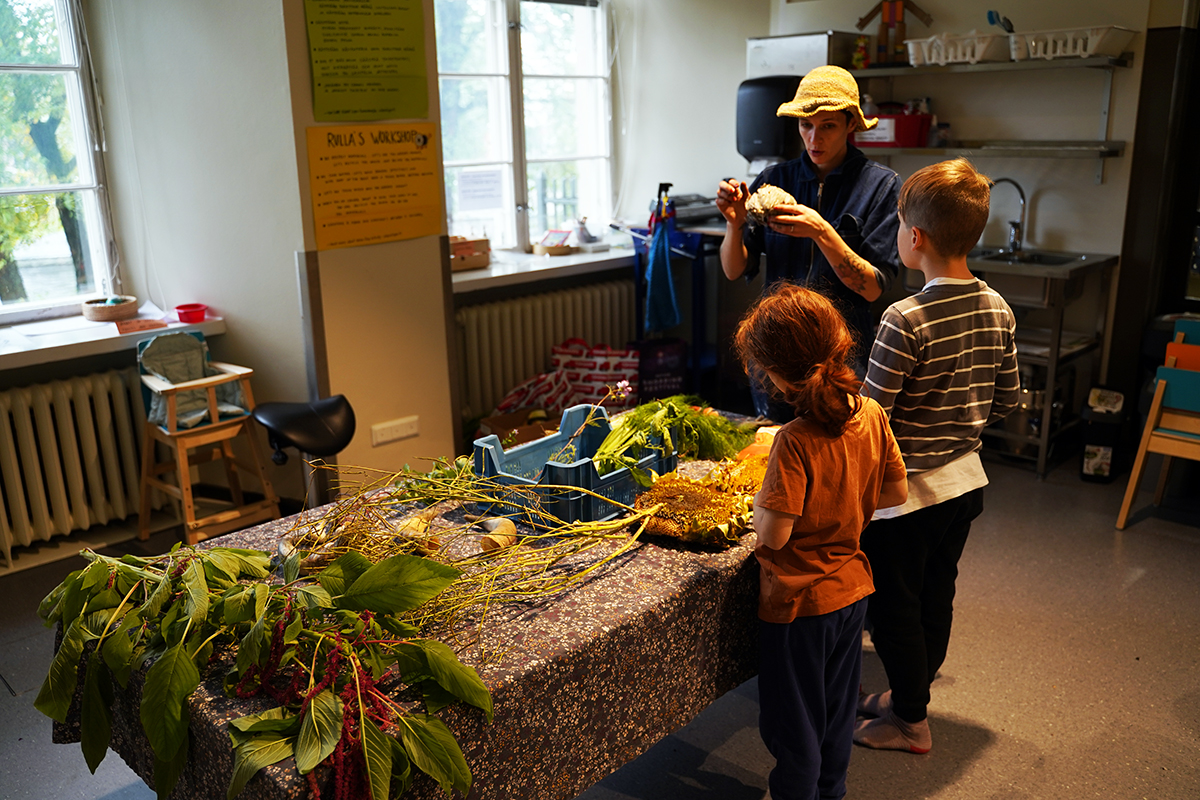 A woman is guiding two children on how to make a minifarm.